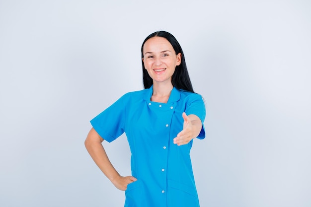 Smiling young doctor is extending hand to camera on white background