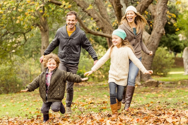 Улыбающаяся молодая семья, впадающая в листья