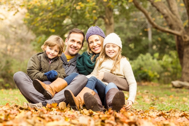 Smiling young family sitting in leaves