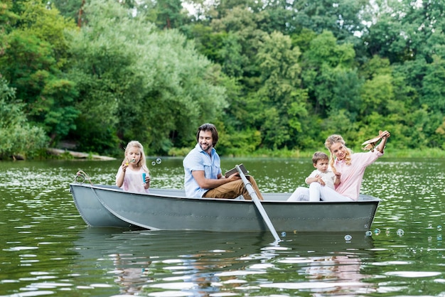 Smiling young family spending time together in boat on lake at park