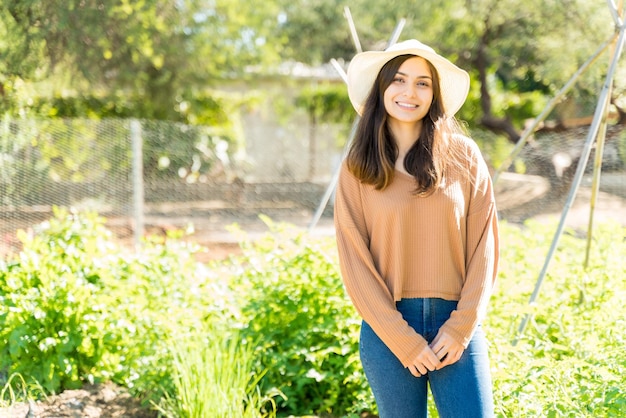 Smiling young farmer standing at vegetable garden during summer