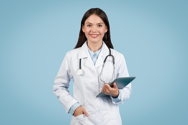 Smiling young female doctor holding tablet and smiling at camera