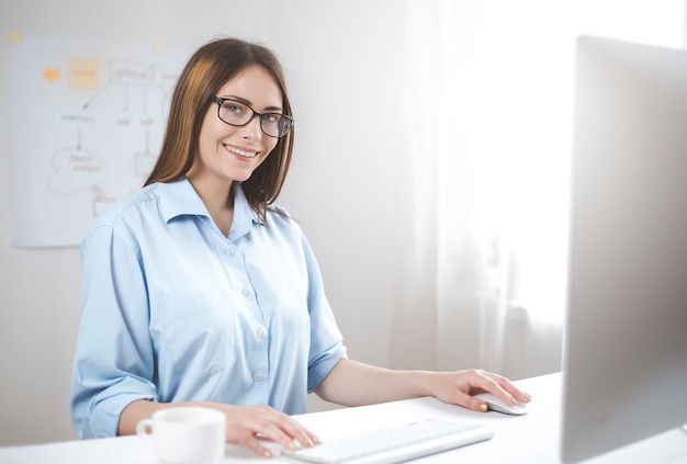 Smiling young female manager working at the computer. Happy business woman 