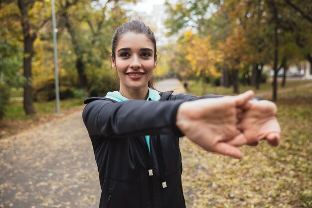 Foto sorridente giovane ragazza fitness facendo esercizi al parco