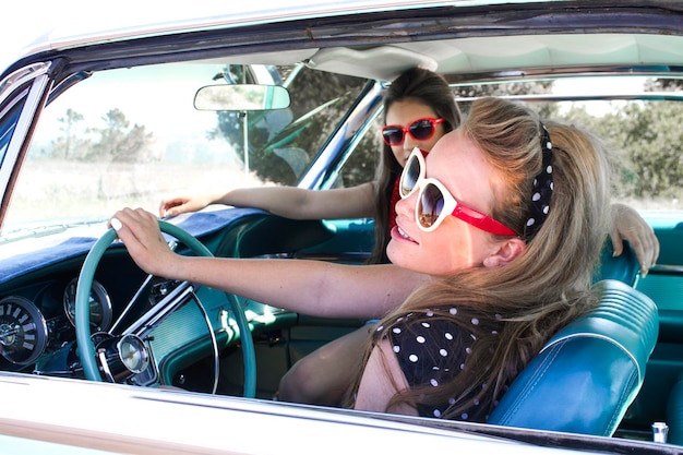 smiling young friends sitting car