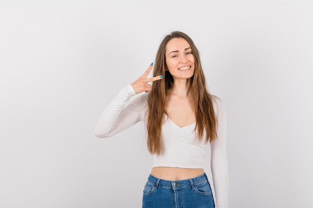 Smiling young girl is showing scissors gesture by smiling on white background