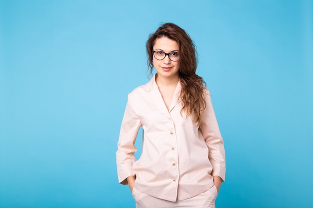 Smiling young girl in pajamas home wear posing while resting at home isolated on blue background