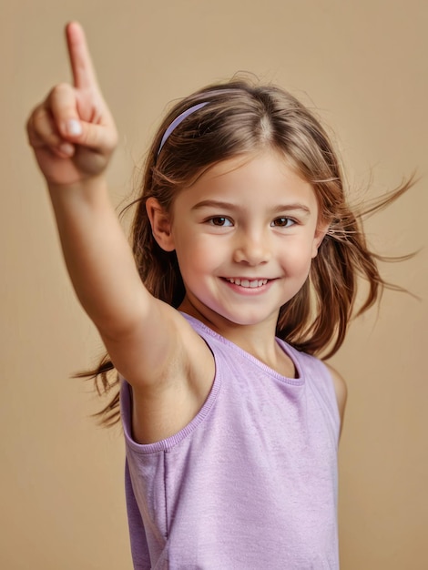 Photo smiling young girl pointing upwards wearing a purple sleeveless top with a beige background