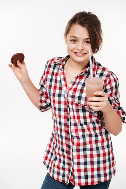 Smiling young girl posing with cookie and cocoa