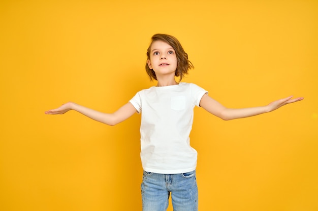 Smiling young girl in white t shirt with her arms opened isolated on yellow background