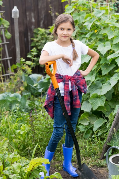 Smiling young girl working at garden with shovel