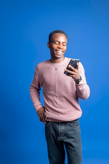 Smiling young good looking African man using smartphone to communicate with family