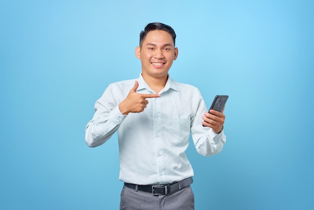 Sorridente giovane uomo d'affari bello che punta il dito sullo smartphone su sfondo blu