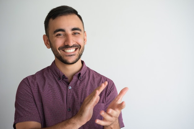 Foto mani d'applauso sorridenti del giovane uomo bello