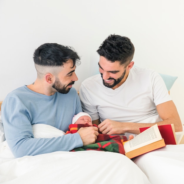 사진 자신의 아기를 사랑하는 침대에 앉아 웃는 젊은 동성애 커플
