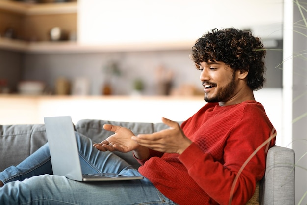 Photo smiling young indian man making video call on laptop at home