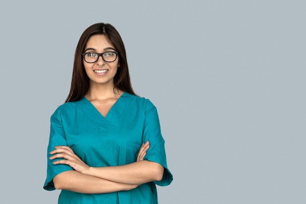 Smiling young indian woman nurse arms crossed look at camera isolated on grey