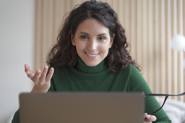 Foto sorridente giovane donna italiana insegnante tutor parla con gli studenti durante la lezione online sul laptop, registra la formazione educativa, piacevole libero professionista che comunica con il cliente tramite videochiamata