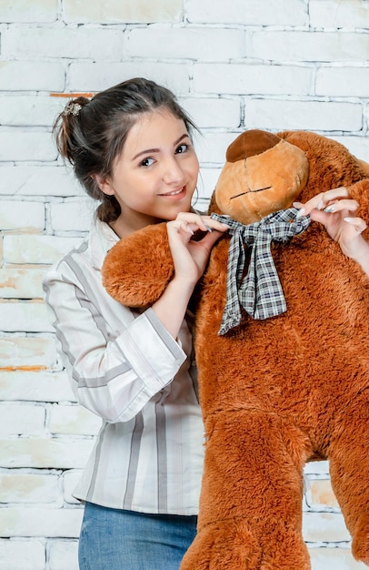 Smiling young lady holding teddy bear and stands on High quality photo