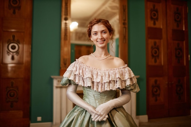 Photo smiling young lady wearing ballgown posing in palace