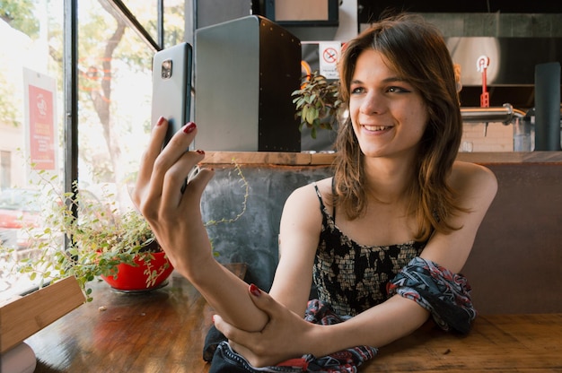 Smiling young latin transgender woman taking a selfie in a restaurant