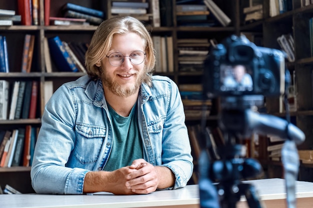 Smiling young male creator blogger talking shooting at professional camera