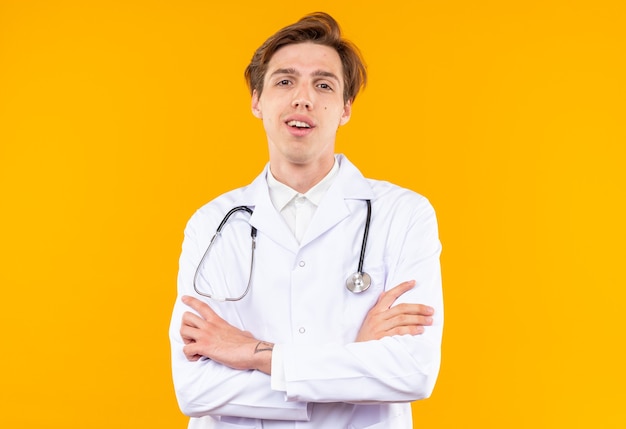 Sorridente giovane medico maschio indossando veste medica con lo stetoscopio che si incrociano le mani