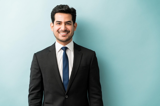 Smiling young male professional standing while making eye contact against colored background