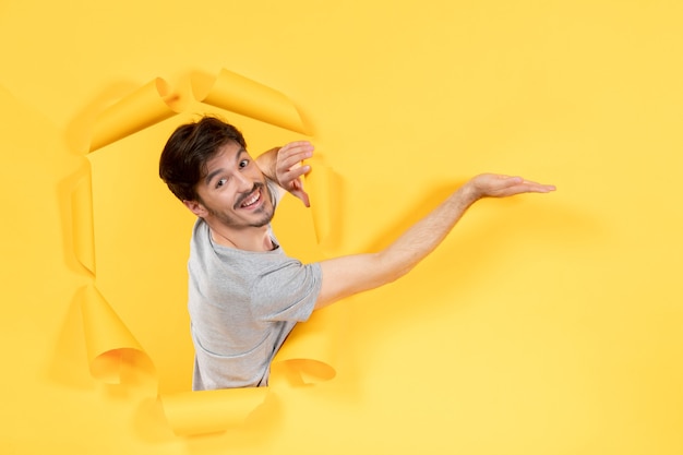 smiling young male on torn yellow paper background indoor handsome facial guy