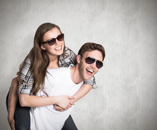 Smiling young man carrying woman against weathered surface