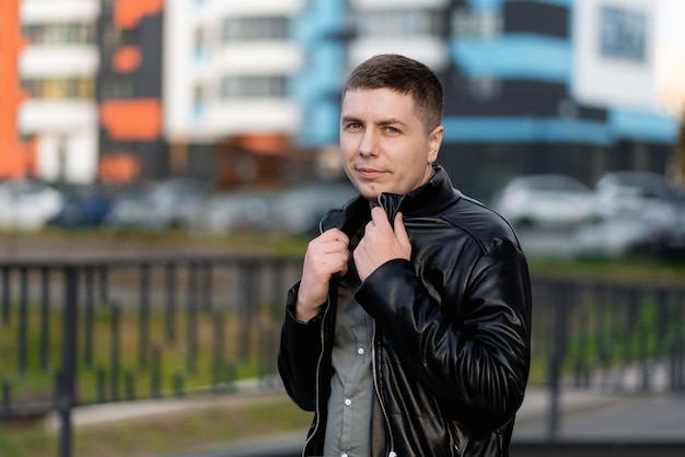 A smiling young man in the city is looking at the camera