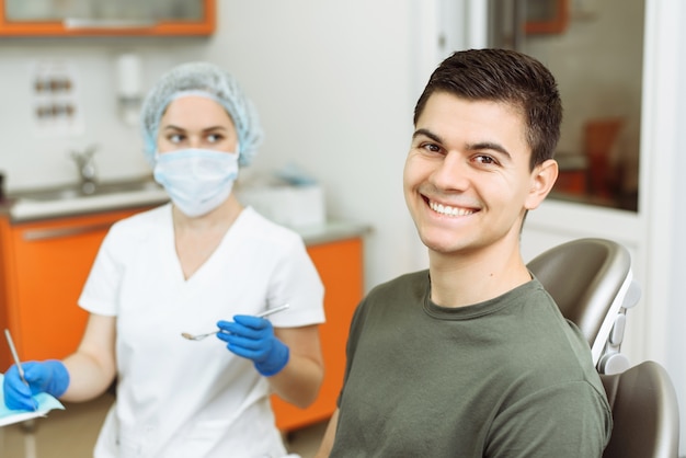 smiling young man in a dentis's chair with the doctor in the background