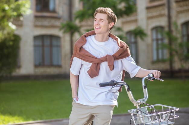 A smiling young man in a ehite tshirt on a bike