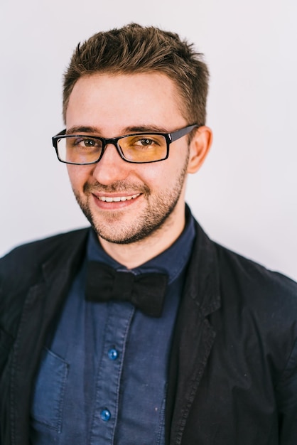 Smiling young man in fashion glasses looks to the camera Shirt and bow tie