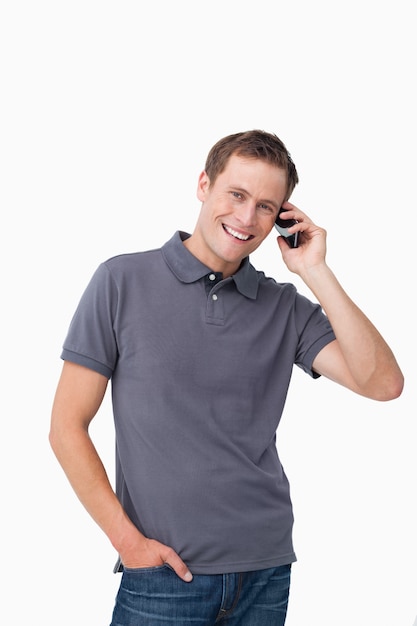 Smiling young man on his mobile phone against a white background