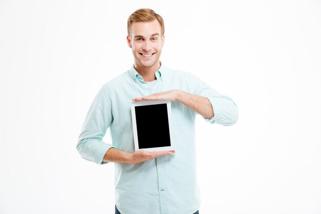 Photo smiling young man holding blank screen tablet over white wall