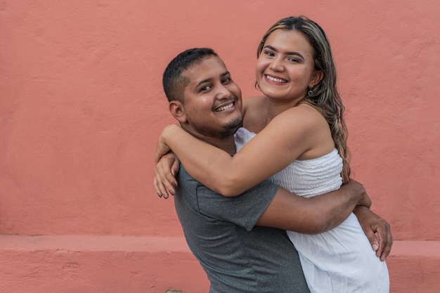 Photo smiling young man holding up his girlfriend in his arms while having fun together in the city