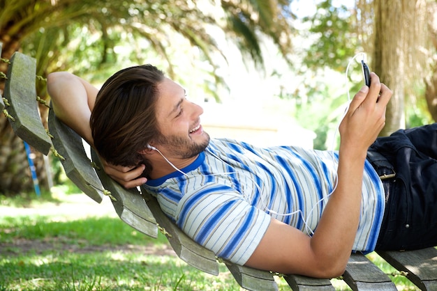 Photo smiling young man lying in hammock with headphones