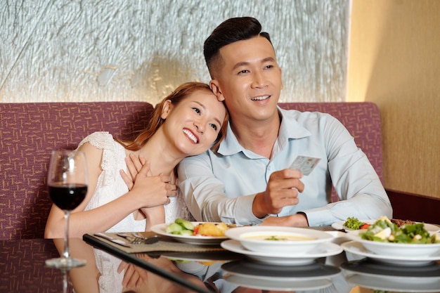 smiling young man paying with credit card for dinner for him and his girlfriend