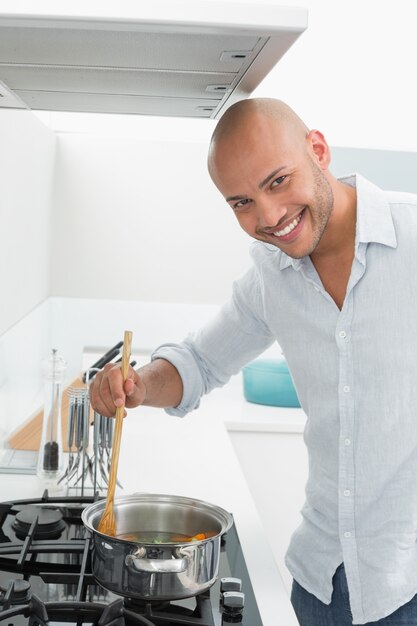 Smiling young man preparing food in kitchen