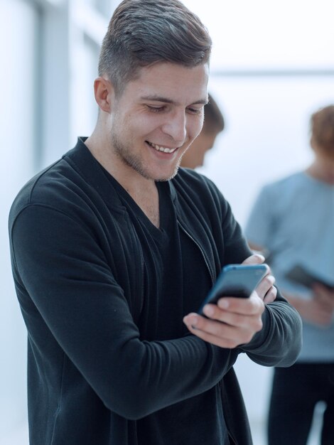 Smiling young man reading a message on his smartphone