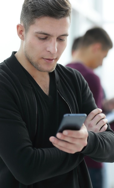 Smiling young man reading a message on his smartphone