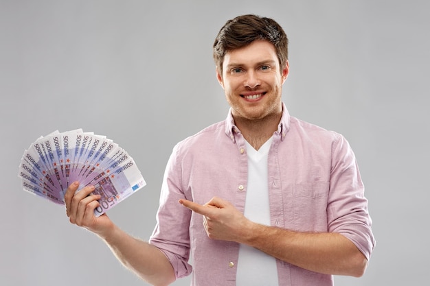 Photo smiling young man showing fan of euro money