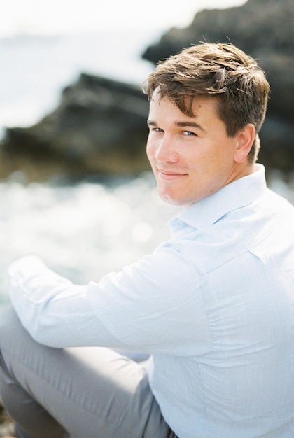 Smiling young man sits on a cliff