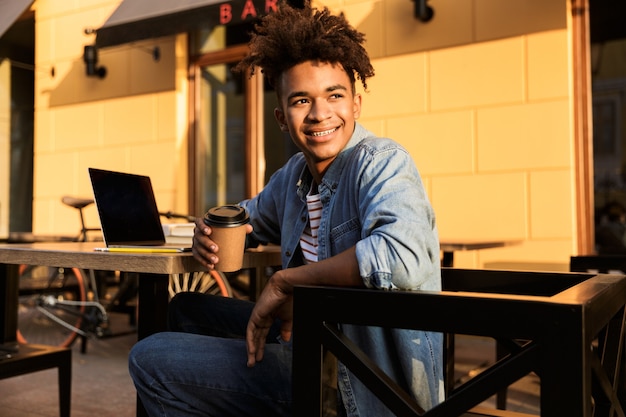 Smiling young man sitting at the cafe outdoors