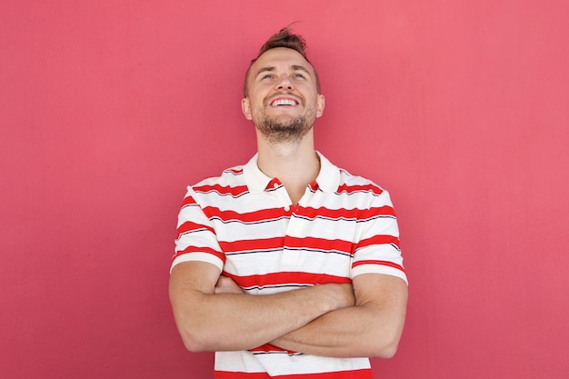 Smiling young man standing against red wall looking up