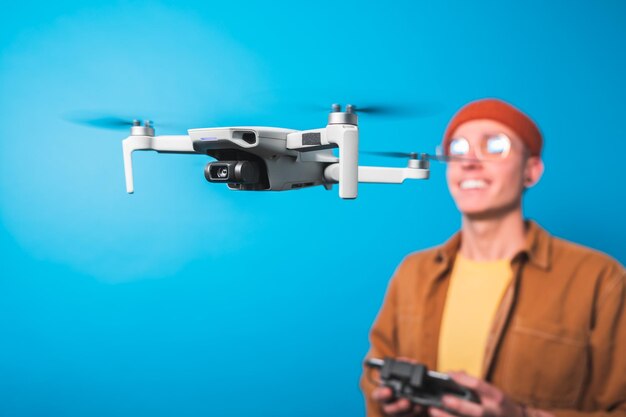 Photo smiling young man training piloting a drone in flight with a remote control