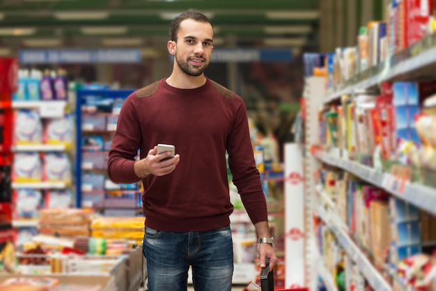 Smiling Young Man Using Mobile Phone While Shopping In Shopping Store