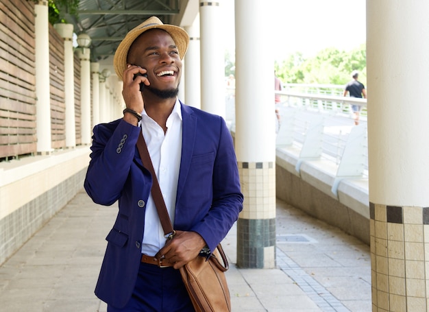 Smiling young man walking and talking on mobile phone