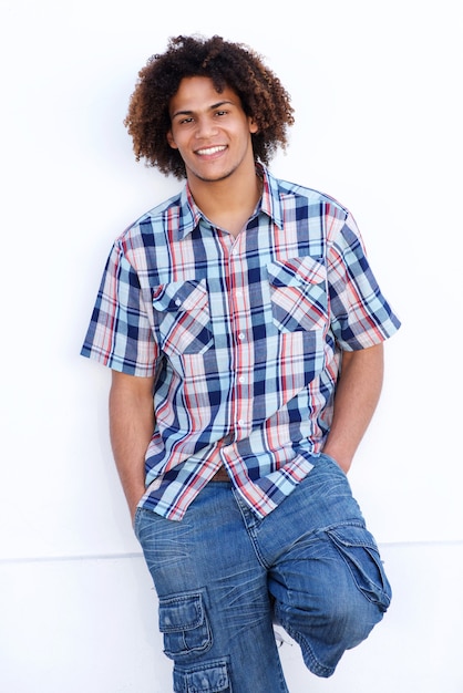 Smiling young man with afro leaning against white wall